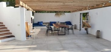 Outdoor dining area with kitchen, table and chairs and lounge sofa at the wall