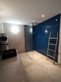 Bathroom with glass walk in shower with blue tales