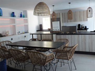 Modern kitchen in wooden style and dining table with rattan chairs