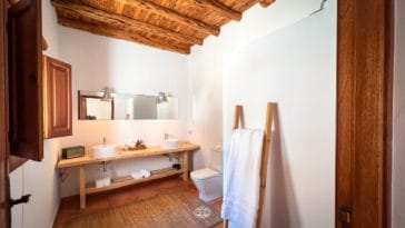 Rustic bathroom with wooden beam roof and double wooden vanity with 2 round sinks