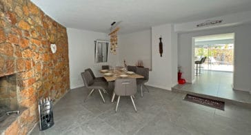 Indoor dining area beside a stone wall with open fire place