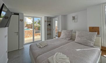 Double bedroom in white and light grey tones with direct access to pool